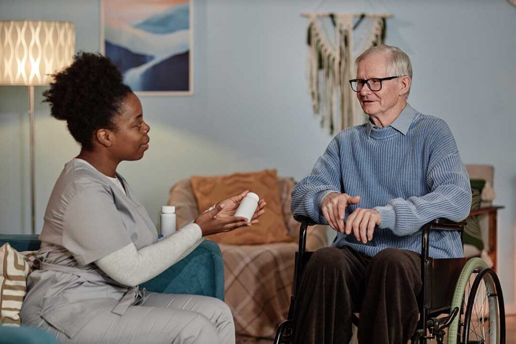 Caregiver reviews a medication chart with an older resident at a bright assisted living table.